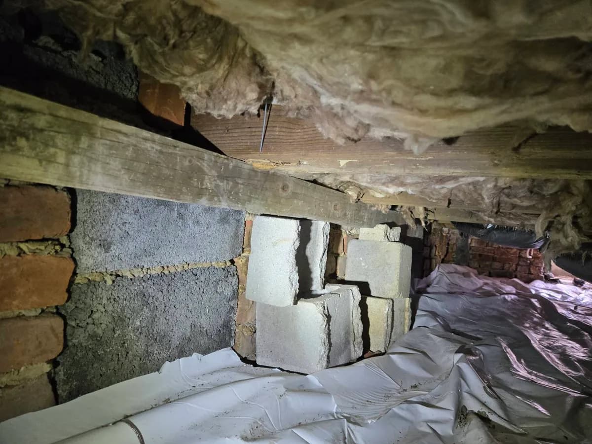 Cracked masonry foundation pier supporting a beam under a home